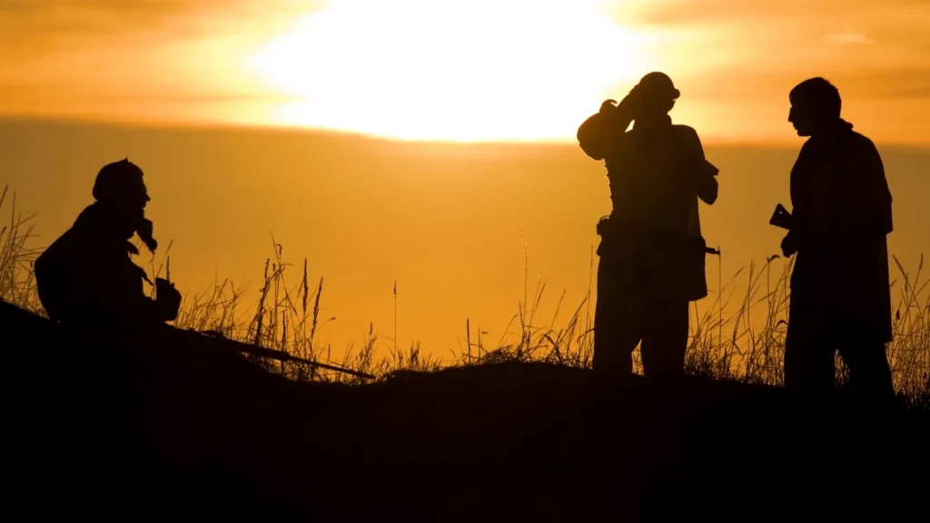 Military Civil War soldiers using hand signals at sunset.