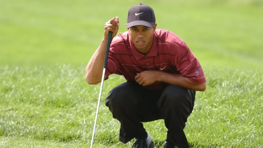 Tiger Woods crouching on a green to read a putt