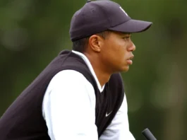 Tiger Woods crouching on grass to read a putt.