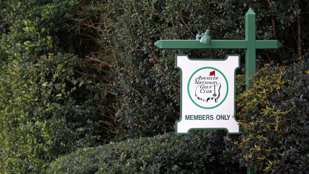 Augusta National Golf Club Members Only sign surrounded by green hedges.