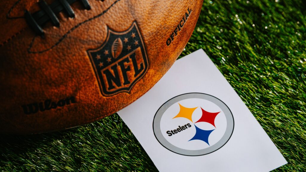 Pittsburgh Steelers NFL team Logo and American football ball on green grass.