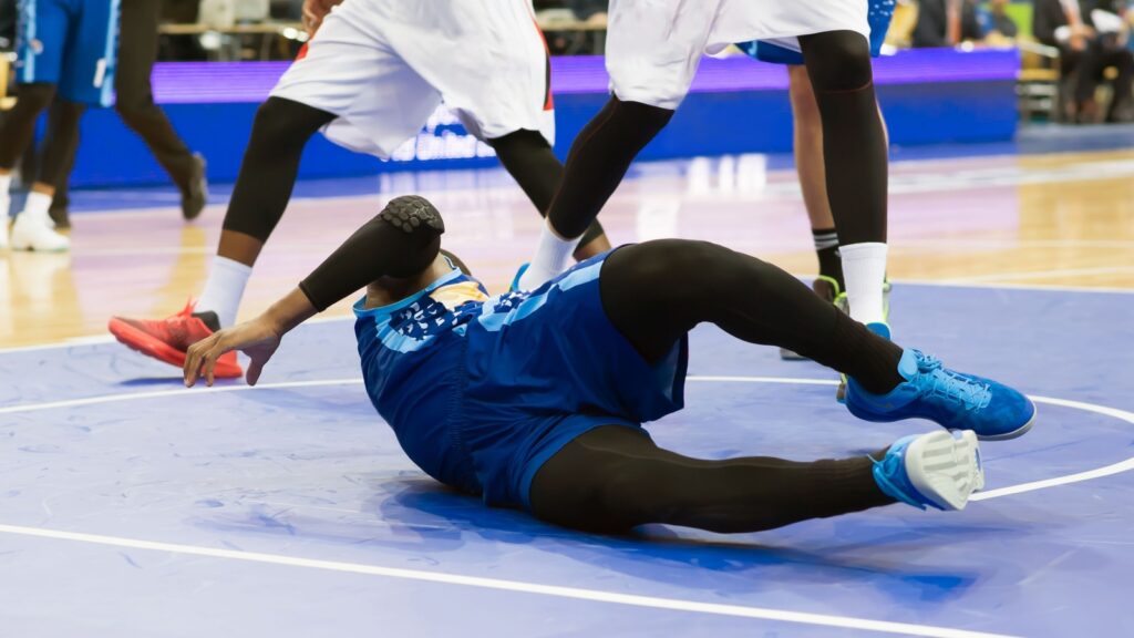 Basketball player falls on the court.