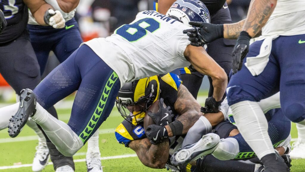 Seattle Seahawks cornerback, Coby Bryant (8), dives over Los Angeles Rams running back, Kyren Williams (23), during an NFL football game.