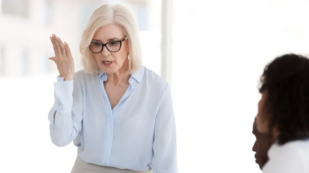 Angry powerful mature boss scolding employees at group corporate