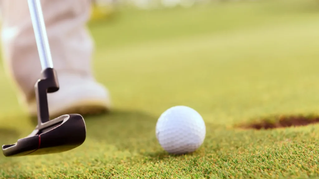 Close up of man putting ball into hole