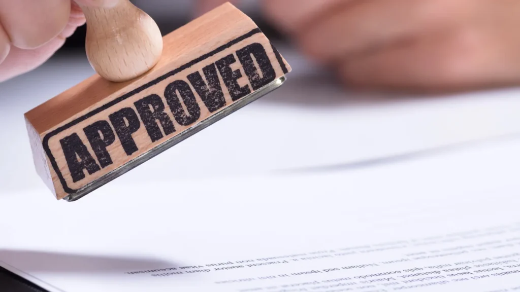 Closeup Of Person Hands Using Stamper On Document With The Text Approved