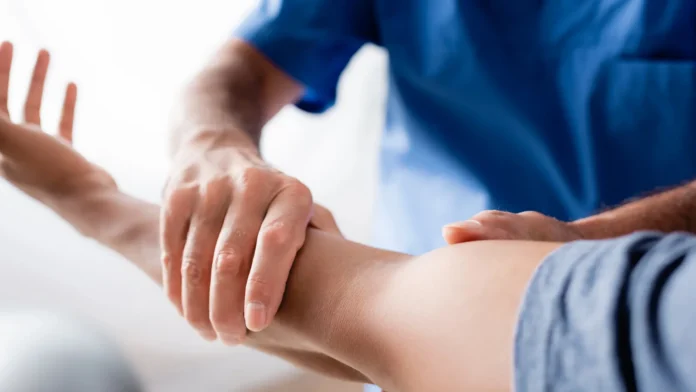 cropped view of chiropractor working with injured arm of african american man in clinic