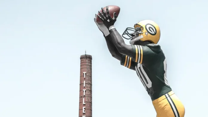 A larger than life 22 foot tall statue of Donald Driver extends his arm upward to catch a pass