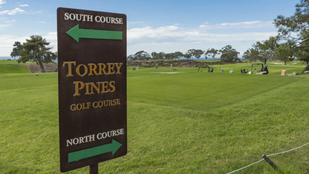 Torrey Pines Golf Course directional signpost with green fairway in the background.