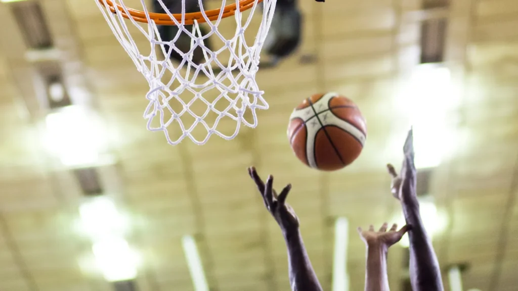 Close-up of a player's hands attempting to throw basketball through the hoop.