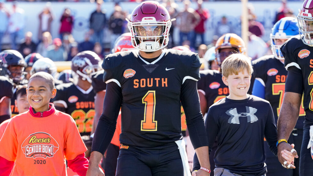 Quarterback Jalen Hurts walks onto the field with children from the Boys and Girls Club prior to the 2020 Reese's Senior Bowl