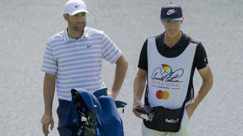 Scottie Scheffler (L) and his caddie Ted Scott wait on the 18th green during the Arnold Palmer Invitational
