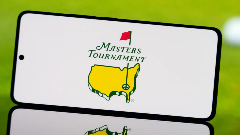 Smartphone displaying Masters Tournament logo with a blurred golf ball and green field in the background