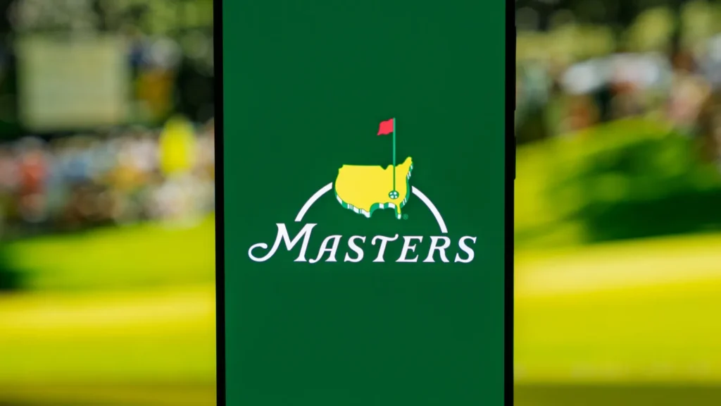 Smartphone displaying The Masters golf tournament logo on a green screen set against a blurred background representing professional sports media and tournament coverage High quality photo