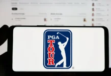 Person holding smartphone with logo of US golf organization PGA Tour on screen in front of website.