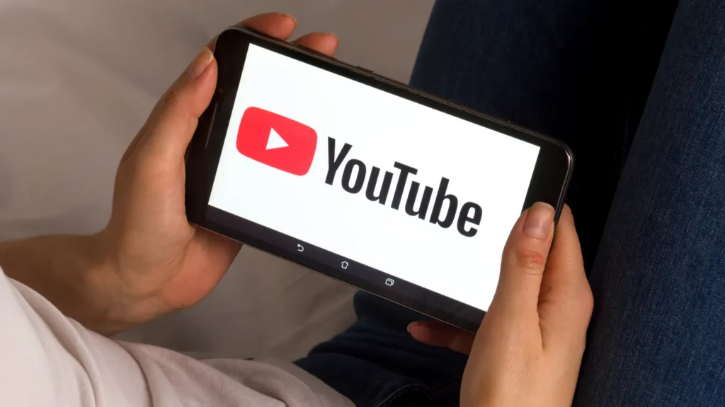 A person holds a tablet with YouTube logo on the screen.