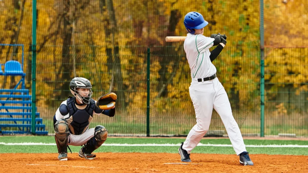 Baseball batter mid-swing with catcher behind home plate.