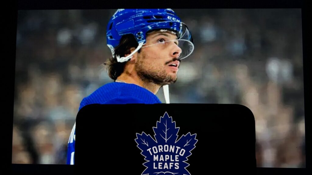 Auston Matthews of the Toronto Maple Leafs looking up while wearing his blue team helmet and jersey