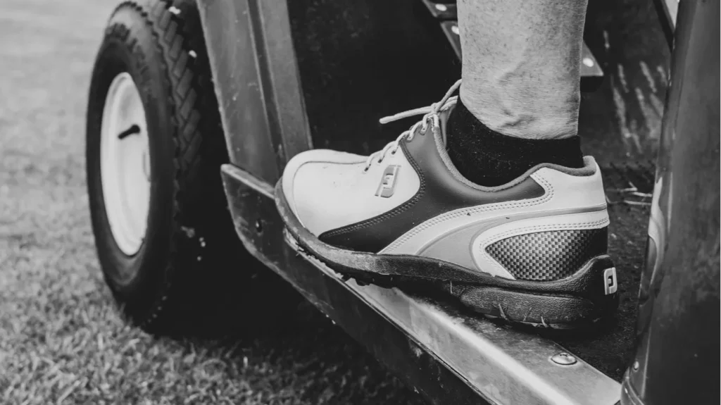 A vertical grayscale shot of a person driving a golf cart