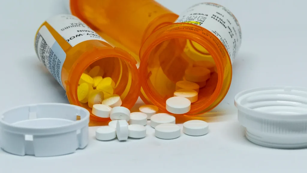Babylon New York USA  15 June 2018 Many bottles of pain relievers taken out of my medicine cabinet that should have been disposed of with pills spilling out of and a whte background