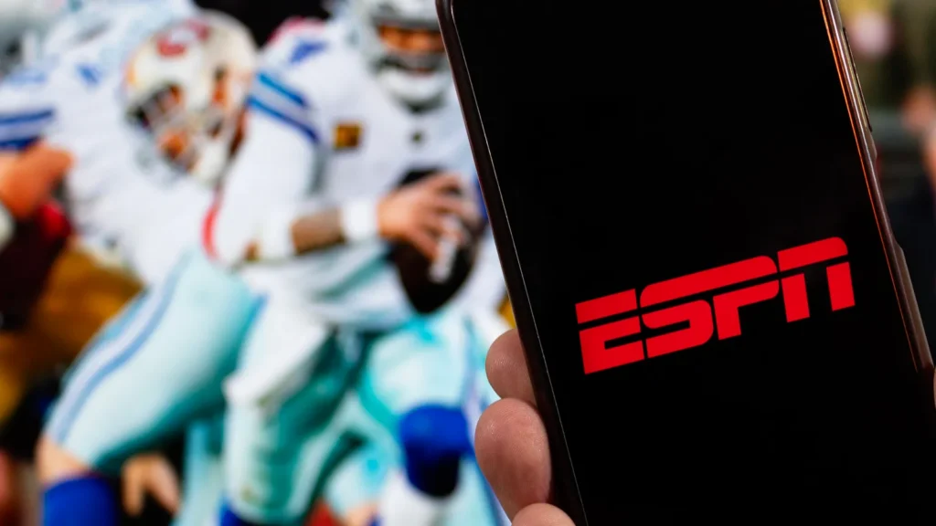 ESPN logo on a mobile phone screen with NFL players in action in the background