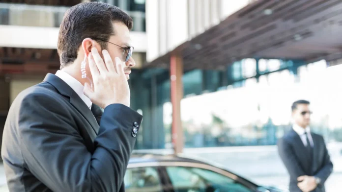 Security agent listening to updates ret service agent listening to updates from security earpiece while waiting by car Security agent listening to updates