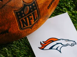 Denver Broncos NFL team Logo and NFL American football ball on green grass