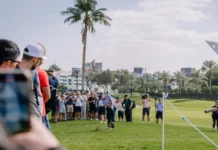 Dubai United Arab Emirates  January 16 2026 Crowd at a golf tournament watches a player on the green with palm trees and modern buildings visible