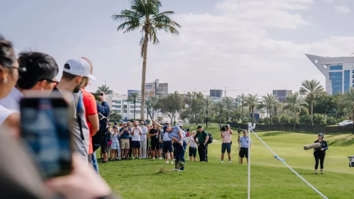 Dubai United Arab Emirates January 16 2026 Crowd at a golf tournament watches a player on the green with palm trees and modern buildings visible Dubai United Arab Emirates January 16 2026 Crowd at a golf tournament watches a player on the green with palm trees and modern buildings visible
