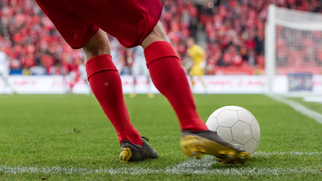 Footballer takes the corner Detail of players legs and the ball during soccer match