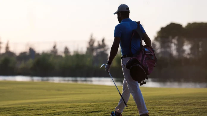 golfer walking and carrying golf bag at beautiful sunset
