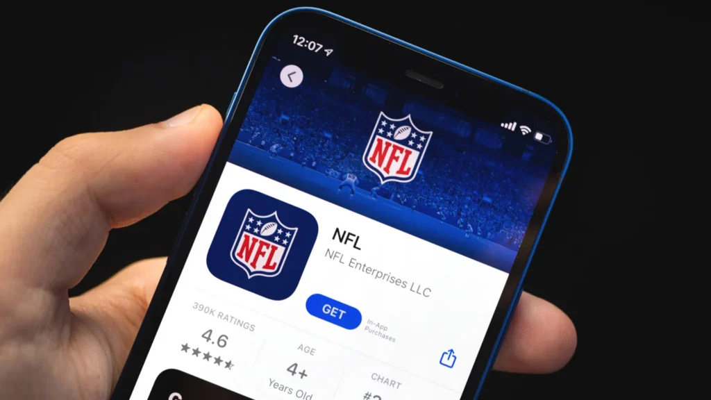 Man holds mobile phone in his hand with NFL application on the screen.