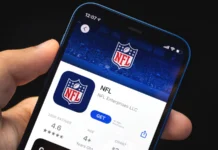 Man holds mobile phone in his hand with NFL application on the screen.