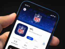 Man holds mobile phone in his hand with NFL application on the screen