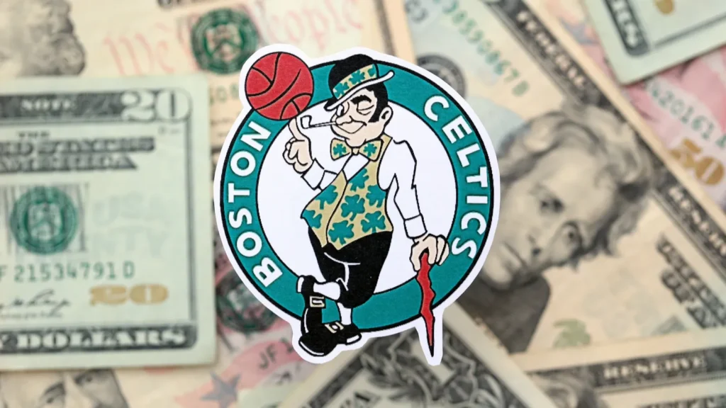 KYIV UKRAINE  FEBRUARY 23 2025 Boston Celtics basketball team badge lies on big amount of US dollar bills close up