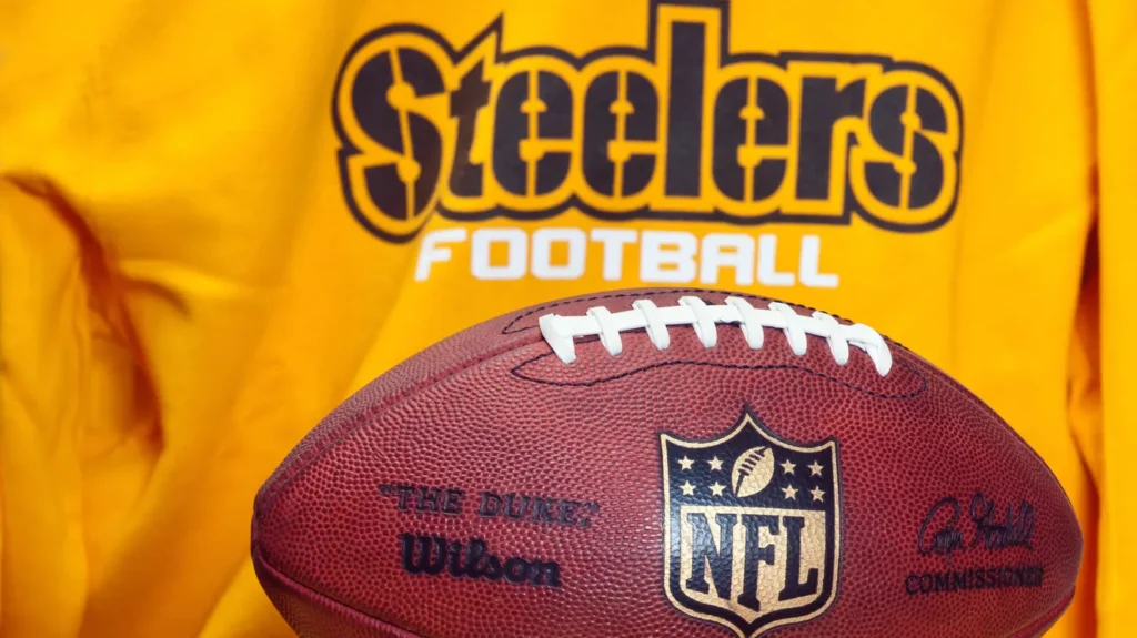NFL football with Pittsburgh Steelers' logo behind it