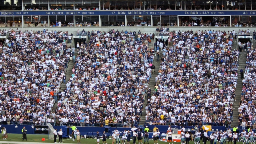 A crowd of spectators in a football stadium, featuring a Dallas Cowboys Ring of Honor section.
