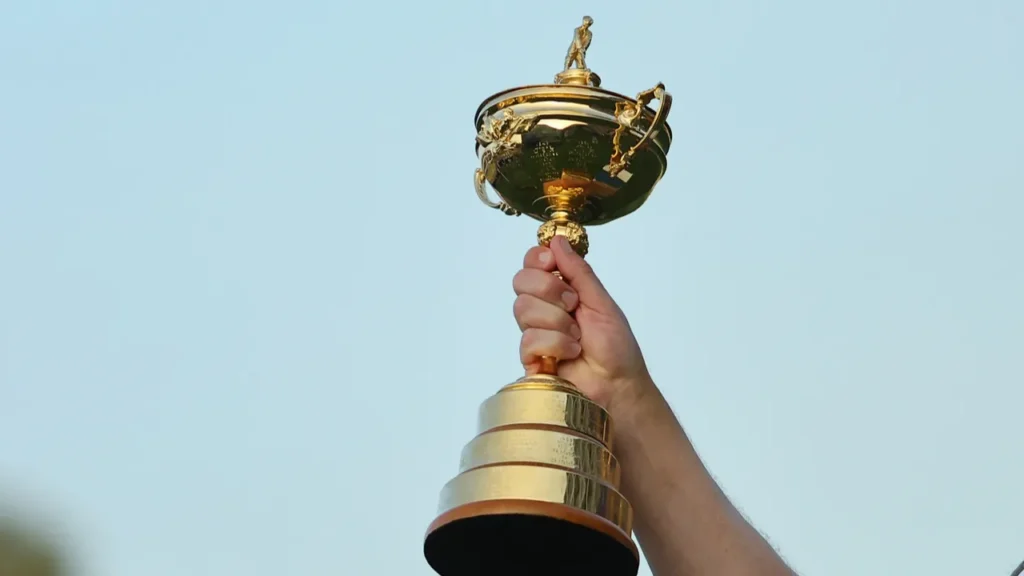A person holding a golden trophy in the hand high in the sky.