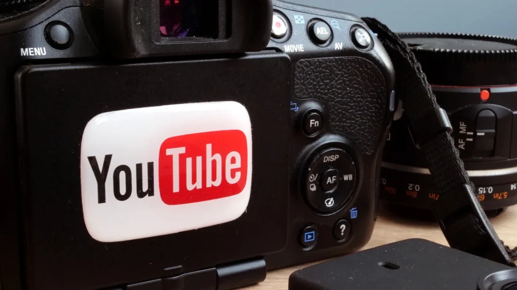A white YouTube logo sticker placed on the back of a black Canon EOS DSLR camera