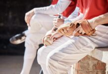 Why MLB teams sometimes bench their hottest hitters at the worst possible time Baseball players in white pants and red jerseys sitting on a bench with a glove and ball.