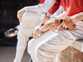 Why MLB teams sometimes bench their hottest hitters at the worst possible time Baseball players in white pants and red jerseys sitting on a bench with a glove and ball.