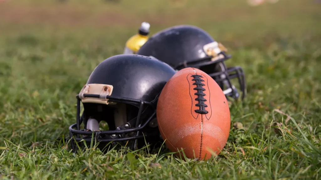 American football helmets and ball lying on field