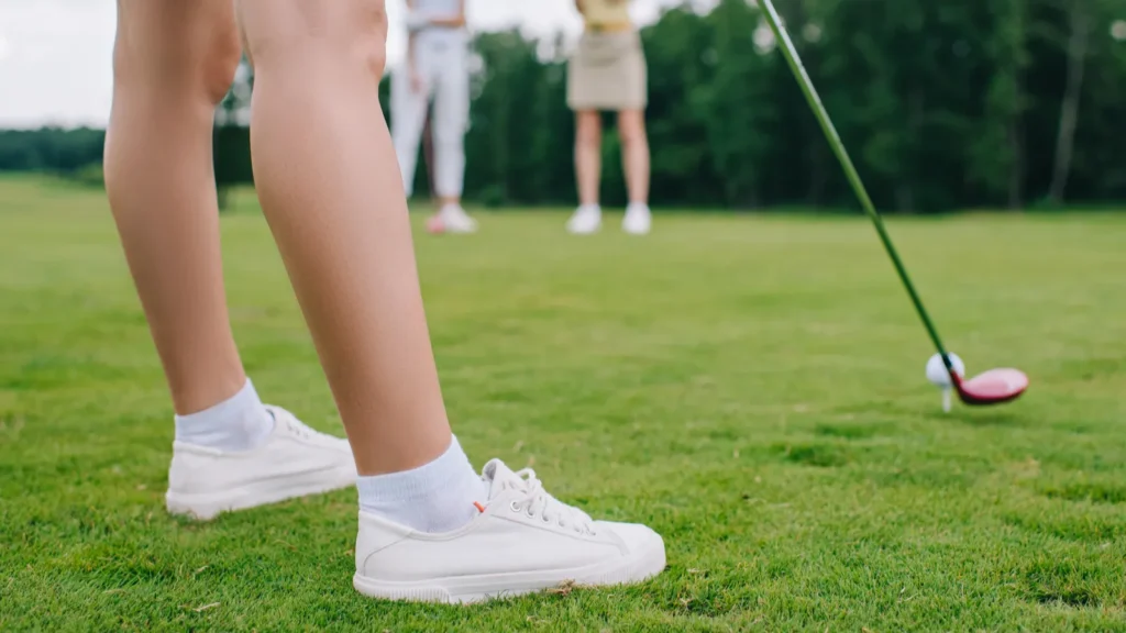 cropped shot of woman playing golf while friends standing near