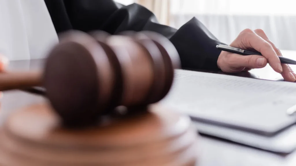 Partial view of a judge holding a pen with the legal papers nearby.