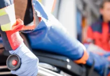 Selective focus of paramedic in latex glove holding stretcher.