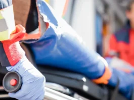 Selective focus of paramedic in latex glove holding stretcher.