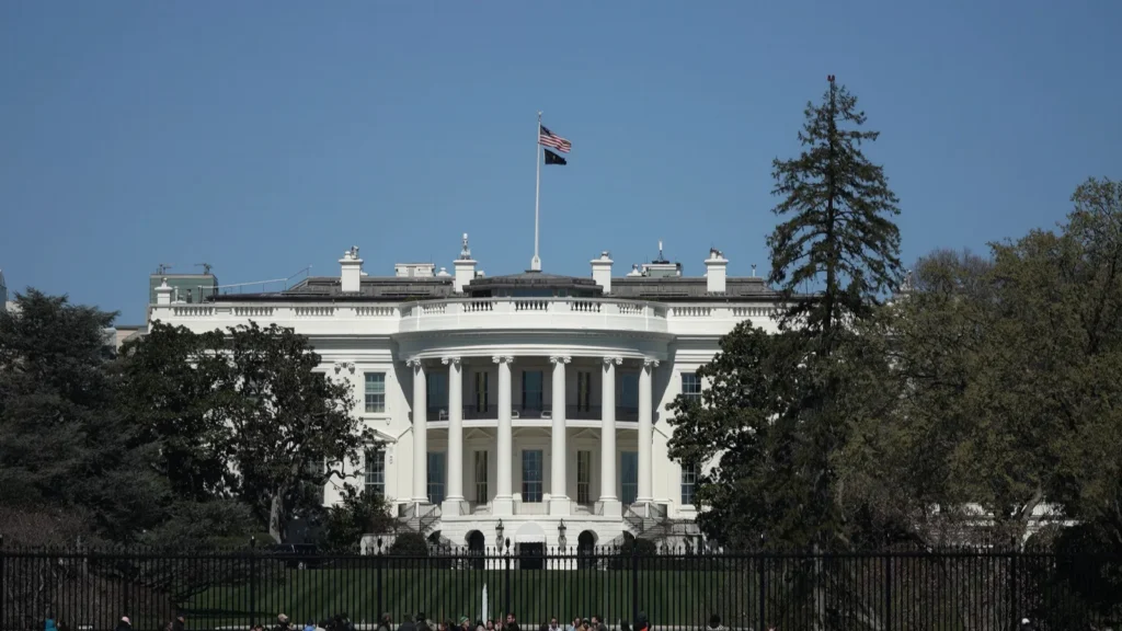 The image shows the White House in Washington, D.C., viewed from the South Lawn