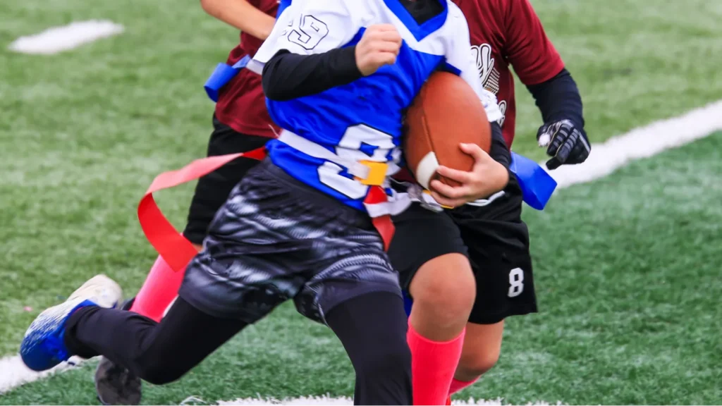 young boy running with the football during a youth flag