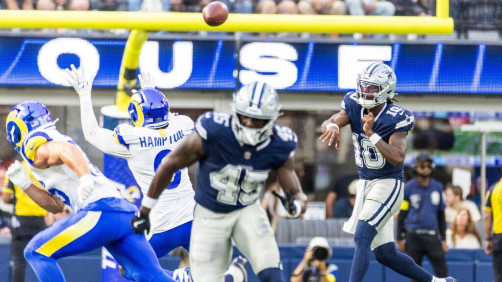 Dallas Cowboys player in navy jumps to catch a pass as Rams defenders converge, ball in midair near the goal line