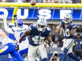 Dallas Cowboys player in navy jumps to catch a pass as Rams defenders converge, ball in midair near the goal line